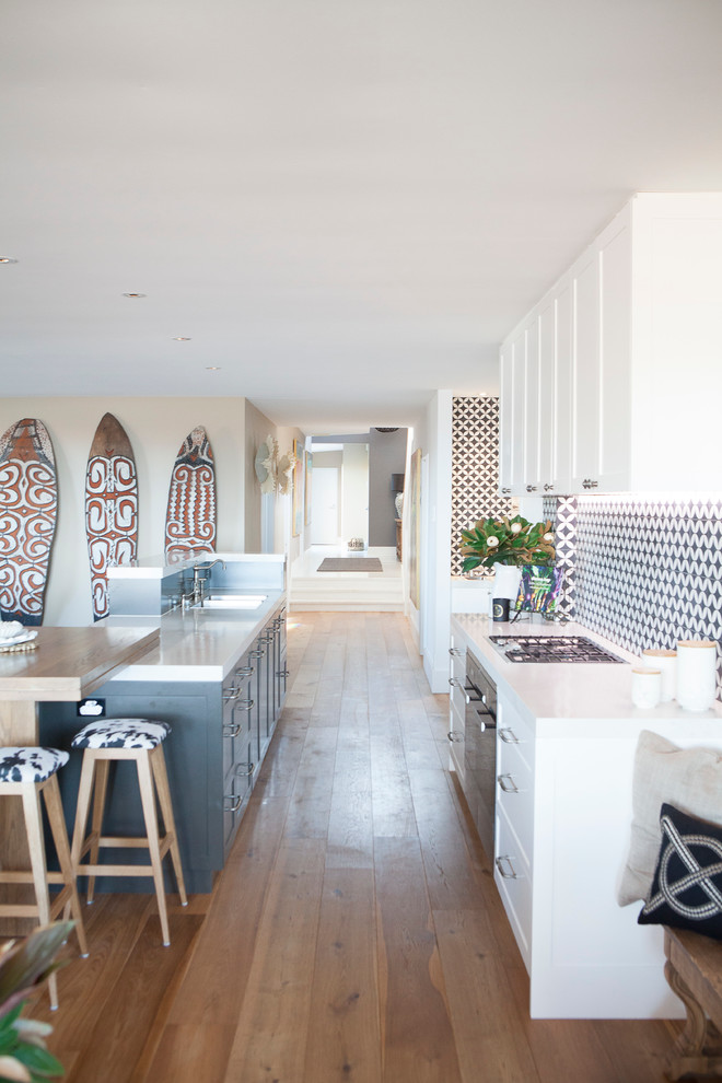 Photo of a large beach style galley eat-in kitchen in Sydney with a double-bowl sink, shaker cabinets, white cabinets, quartz benchtops, brown splashback, ceramic splashback, stainless steel appliances, medium hardwood floors and with island.