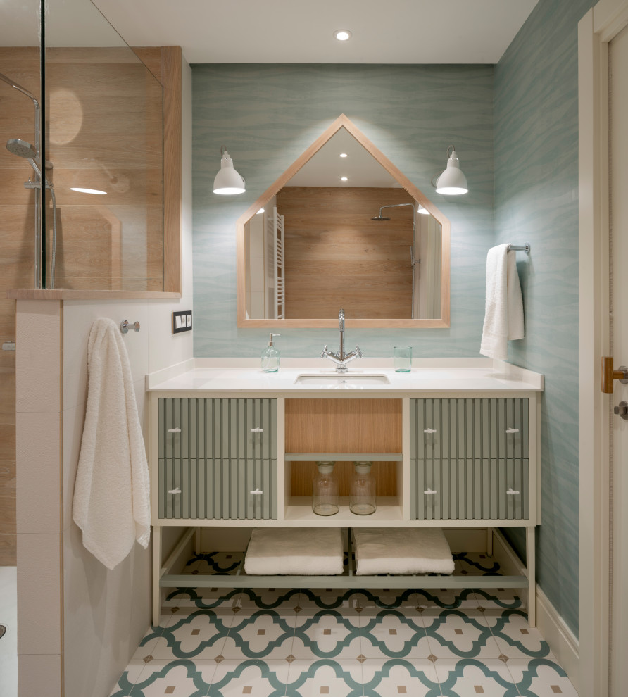 Design ideas for a mid-sized scandinavian kids bathroom in Bilbao with furniture-like cabinets, white cabinets, an alcove tub, a curbless shower, a wall-mount toilet, blue tile, blue walls, porcelain floors, an undermount sink, engineered quartz benchtops, blue floor, a hinged shower door, white benchtops, a single vanity, a built-in vanity and wallpaper.