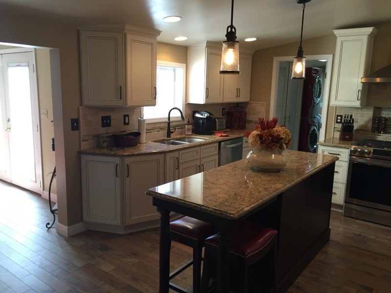 Eat-in kitchen - mid-sized transitional u-shaped medium tone wood floor eat-in kitchen idea with an undermount sink, flat-panel cabinets, dark wood cabinets, quartz countertops, beige backsplash, stone tile backsplash, stainless steel appliances and an island