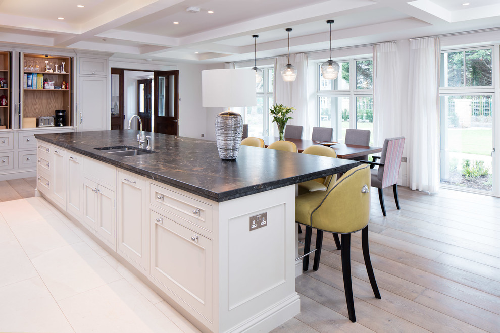 Large traditional u-shaped eat-in kitchen in Dublin with an undermount sink, shaker cabinets, limestone benchtops, stone slab splashback, black appliances, medium hardwood floors and with island.