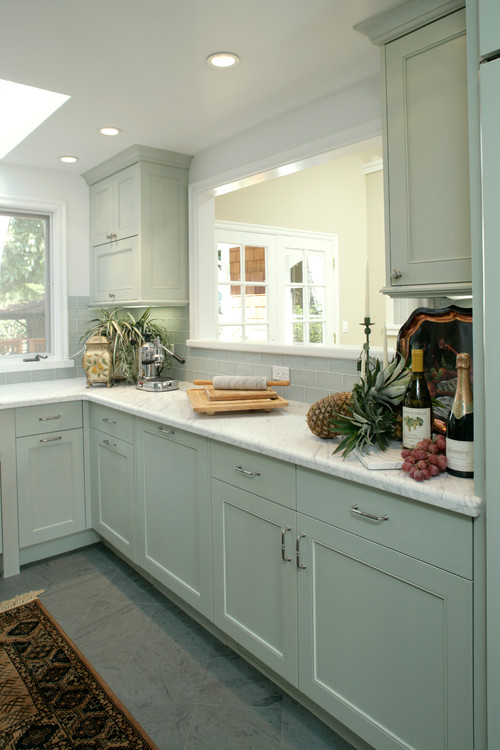 Light green shaker kitchen cabinets with white marble countertop and soft gray subway tile backsplash in a bright, airy kitchen