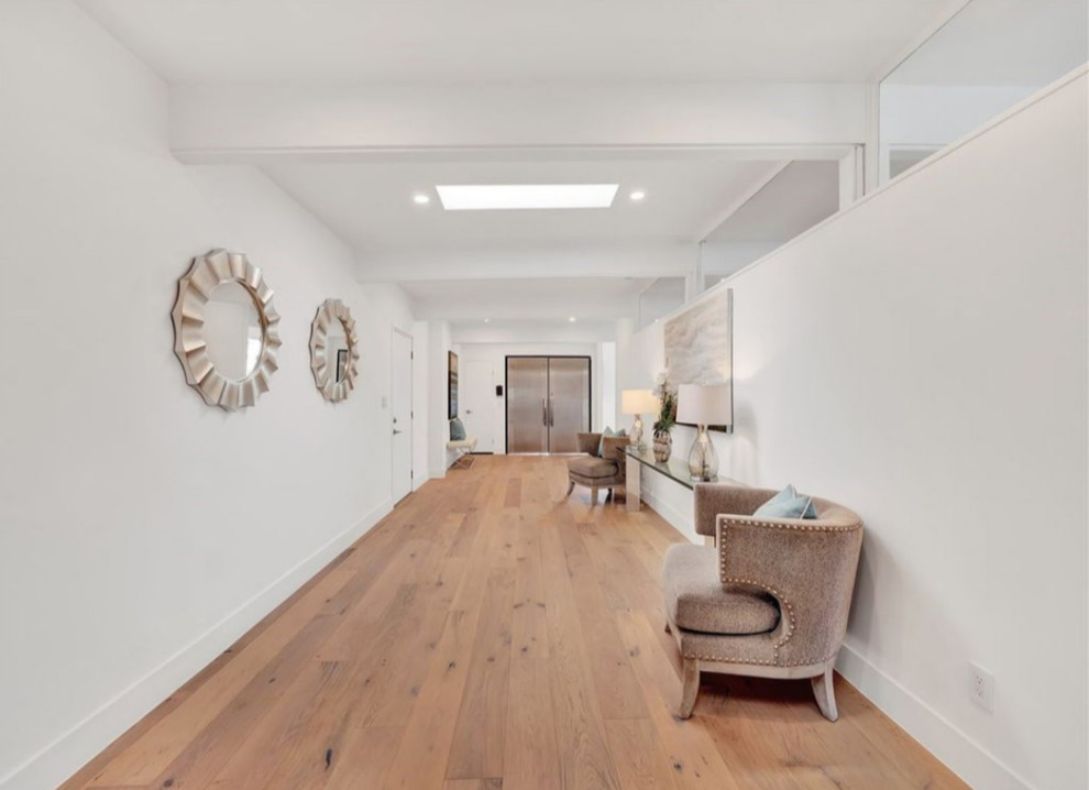 Large modern foyer in Los Angeles with white walls, light hardwood floors, a single front door and brown floor.
