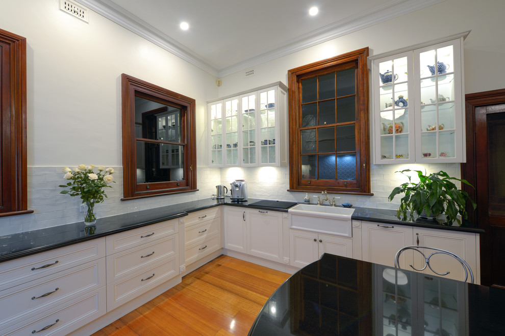 Expansive victorian u-shaped eat-in kitchen in Newcastle - Maitland with a farmhouse sink, recessed-panel cabinets, white cabinets, granite benchtops, white splashback, subway tile splashback, medium hardwood floors and with island.