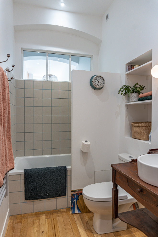 Idéer för ett litet retro brun en-suite badrum, med ett undermonterat badkar, en toalettstol med hel cisternkåpa, beige kakel, vita väggar, ljust trägolv, ett nedsänkt handfat och träbänkskiva