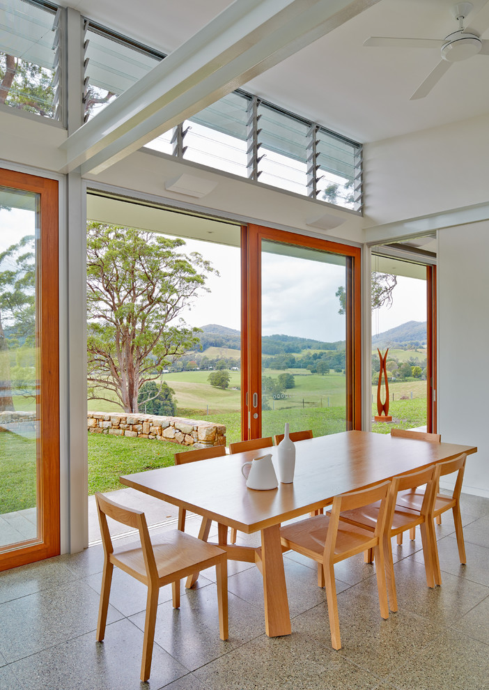 Large contemporary open plan dining in Sydney with white walls, concrete floors and a two-sided fireplace.