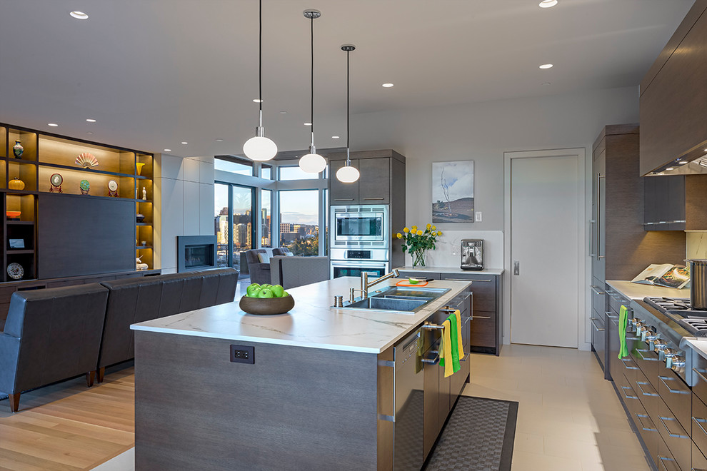 Large modern l-shaped kitchen in Seattle with a drop-in sink, flat-panel cabinets, dark wood cabinets, quartzite benchtops, white splashback, stone slab splashback, panelled appliances, porcelain floors, with island, beige floor and white benchtop.
