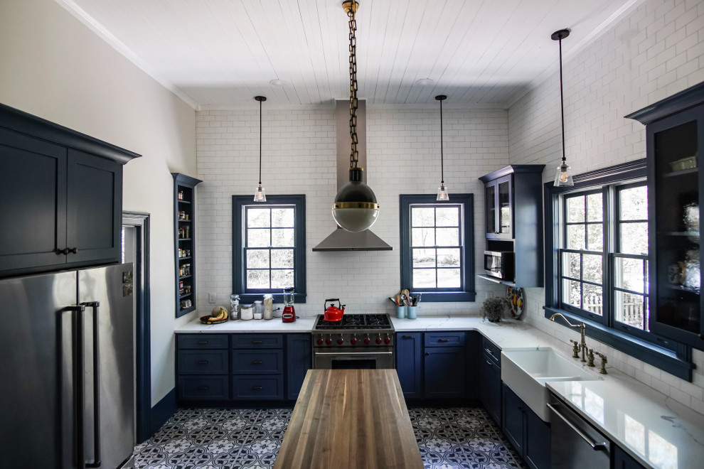 Inspiration for a mid-sized traditional u-shaped kitchen pantry in Atlanta with a farmhouse sink, glass-front cabinets, blue cabinets, marble benchtops, white splashback, porcelain splashback, stainless steel appliances, slate floors, with island, white floor and white benchtop.