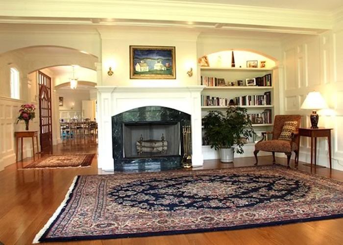 This is an example of a beach style living room in Boston with white walls, medium hardwood floors, a standard fireplace and a plaster fireplace surround.