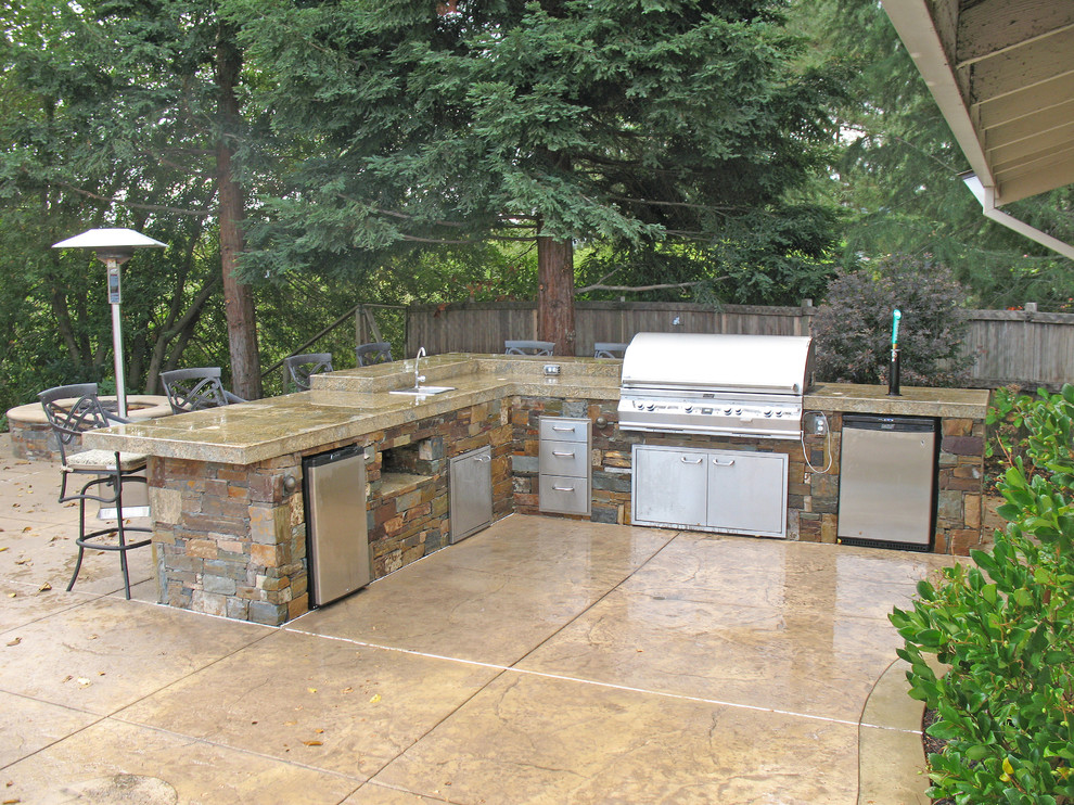 This is an example of a mid-sized country backyard patio in San Francisco with an outdoor kitchen, stamped concrete and no cover.