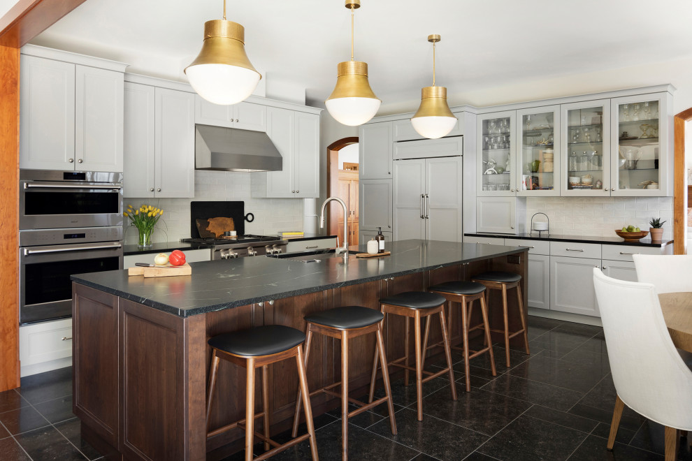 Example of a large transitional single-wall porcelain tile, black floor and exposed beam eat-in kitchen design in Minneapolis with an undermount sink, recessed-panel cabinets, granite countertops, metallic backsplash, mirror backsplash, paneled appliances, an island and black countertops