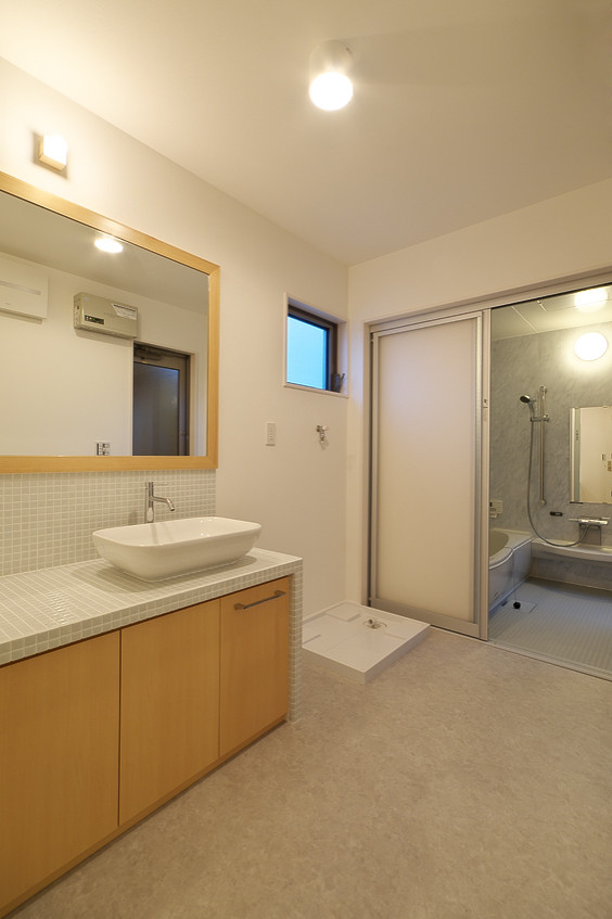 Foto på ett mellanstort nordiskt grå toalett, med släta luckor, grå skåp, grå kakel, mosaik, vita väggar, vinylgolv, ett nedsänkt handfat, kaklad bänkskiva och grått golv