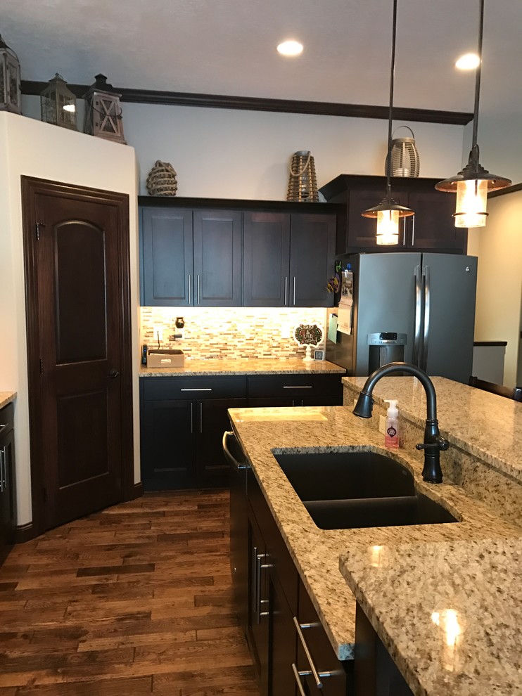Transitional l-shaped kitchen photo with an undermount sink, flat-panel cabinets, dark wood cabinets, granite countertops, multicolored backsplash, ceramic backsplash, stainless steel appliances and an island