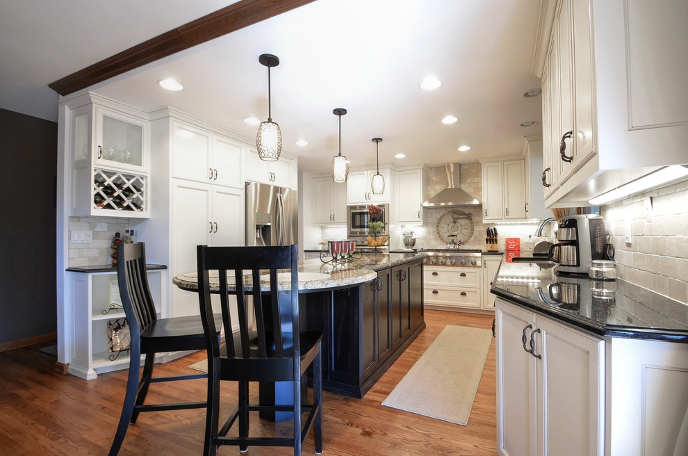 Inspiration for a transitional medium tone wood floor kitchen remodel in Denver with an undermount sink, recessed-panel cabinets, white cabinets, granite countertops, beige backsplash, subway tile backsplash, stainless steel appliances and an island