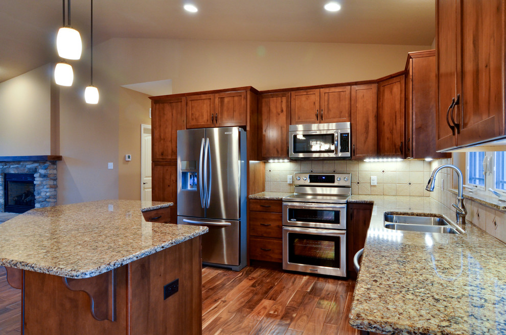 Open concept kitchen - mid-sized rustic l-shaped medium tone wood floor open concept kitchen idea with a double-bowl sink, shaker cabinets, medium tone wood cabinets, quartz countertops, beige backsplash, ceramic backsplash, stainless steel appliances, beige walls and an island