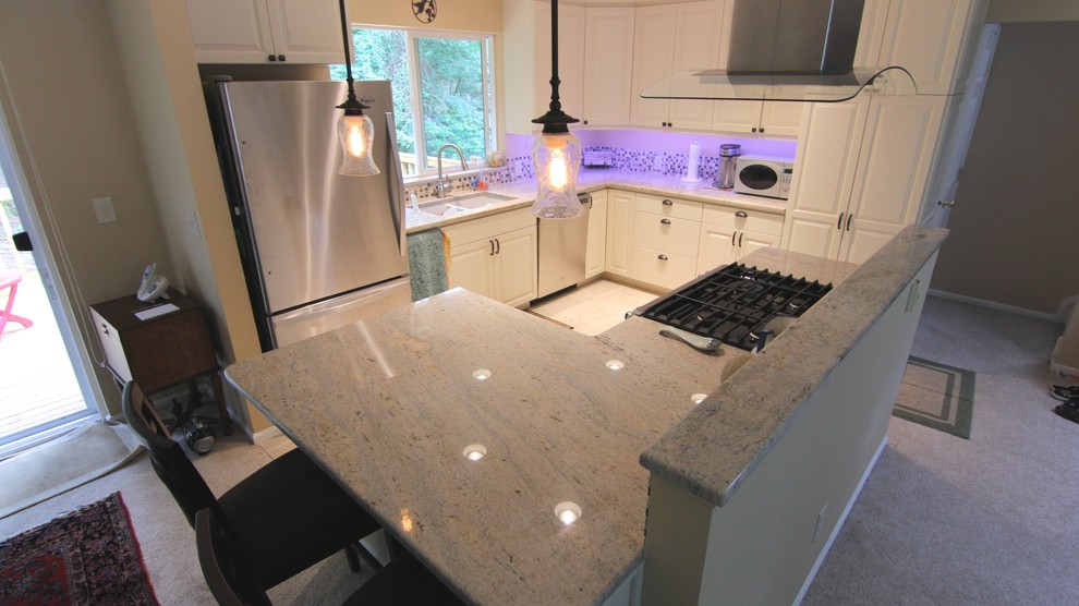 Mid-sized traditional l-shaped eat-in kitchen in Seattle with a double-bowl sink, raised-panel cabinets, white cabinets, granite benchtops, multi-coloured splashback, glass tile splashback, stainless steel appliances, terra-cotta floors and with island.