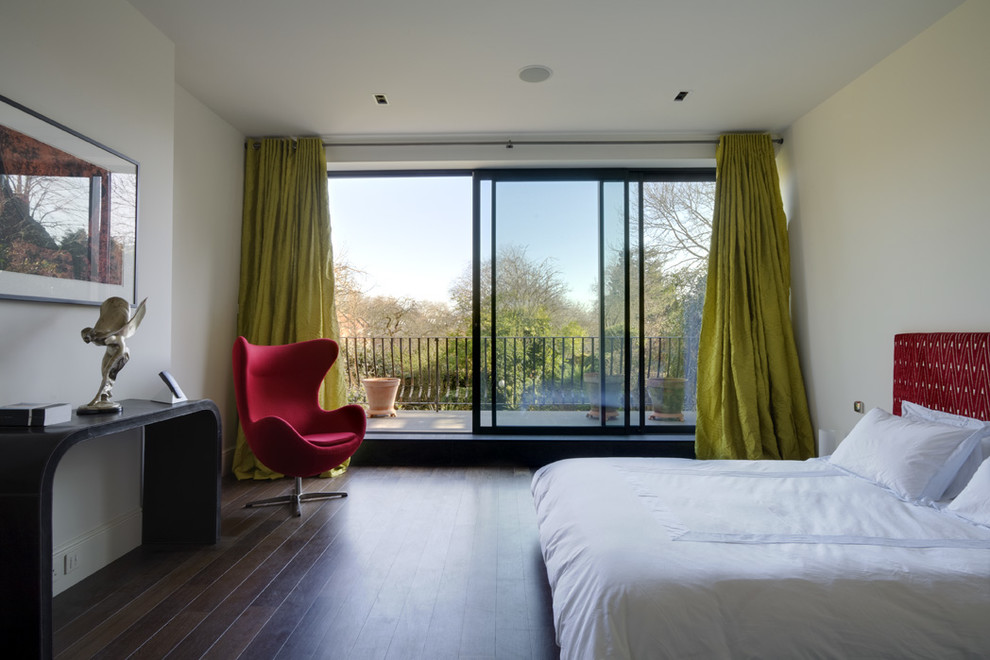 Photo of a large contemporary master bedroom in London with white walls, dark hardwood floors, no fireplace and brown floor.