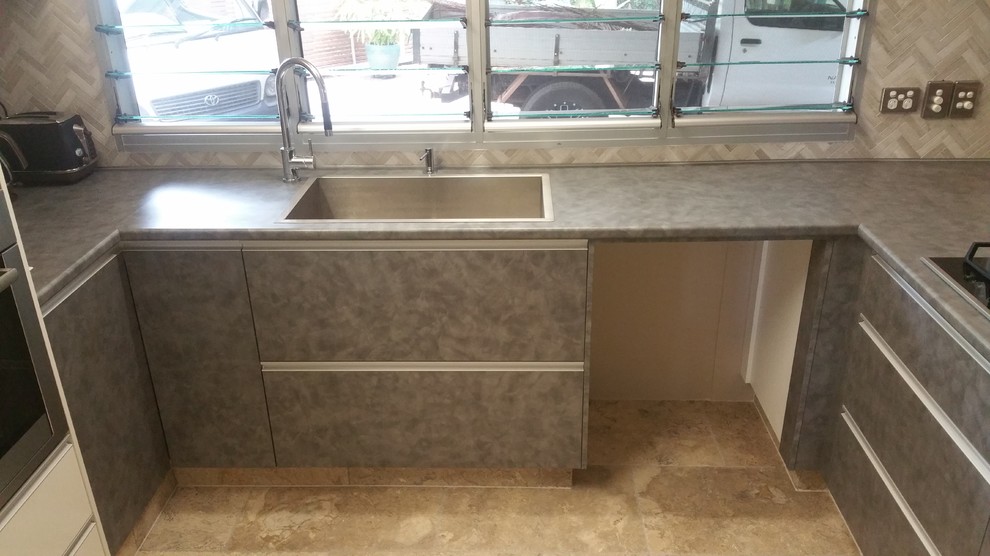 Inspiration for a mid-sized eclectic u-shaped home design in Darwin with a drop-in sink, flat-panel cabinets, blue cabinets, solid surface benchtops, grey splashback, mosaic tile splashback, stainless steel appliances, slate floors and multiple islands.