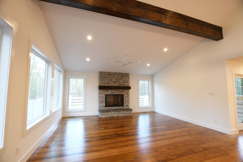 This is an example of a large country open concept living room in New York with white walls, medium hardwood floors, a standard fireplace, brown floor and wood.