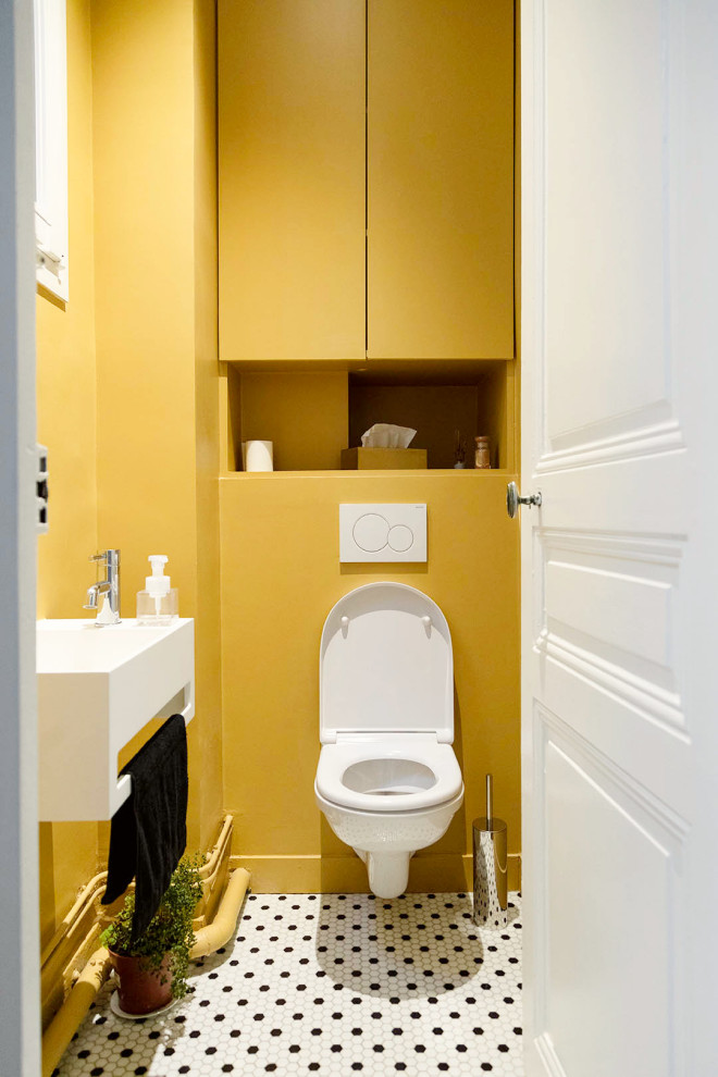 Exemple d'un petit WC suspendu avec un placard à porte affleurante, des portes de placard jaunes, un mur jaune, un sol en carrelage de terre cuite, un lavabo suspendu, un plan de toilette en surface solide, un sol multicolore, un plan de toilette blanc et meuble-lavabo encastré.