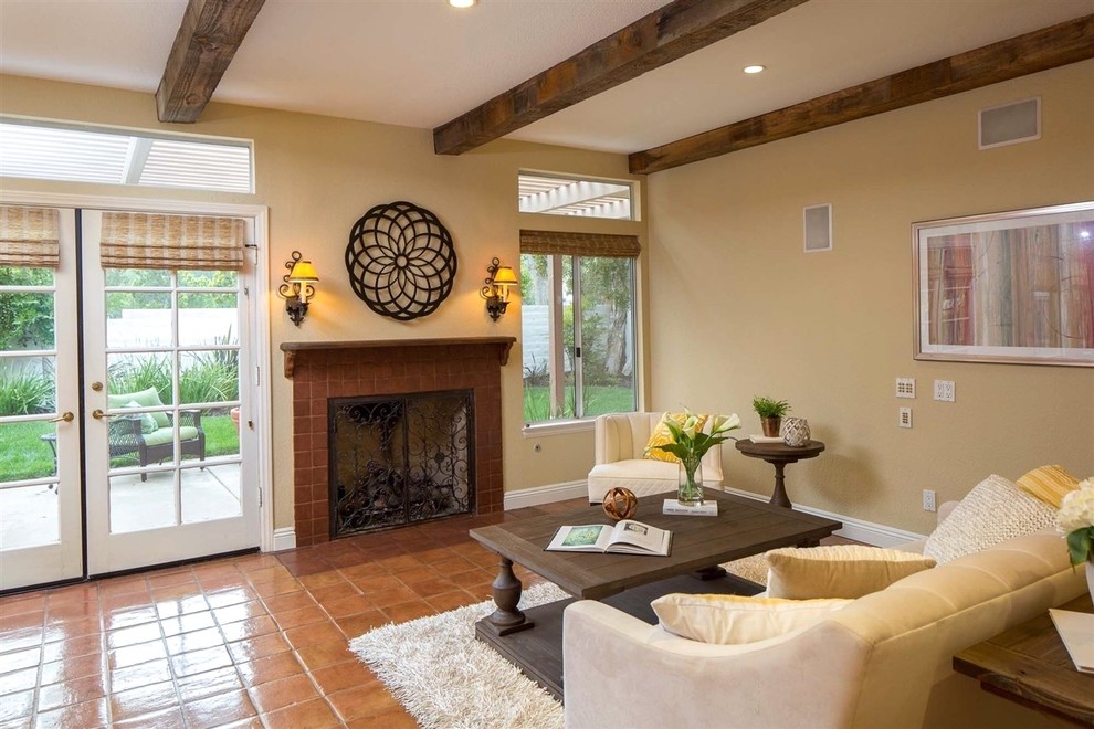 Large mediterranean open concept family room in San Diego with beige walls, terra-cotta floors, a standard fireplace, no tv and orange floor.