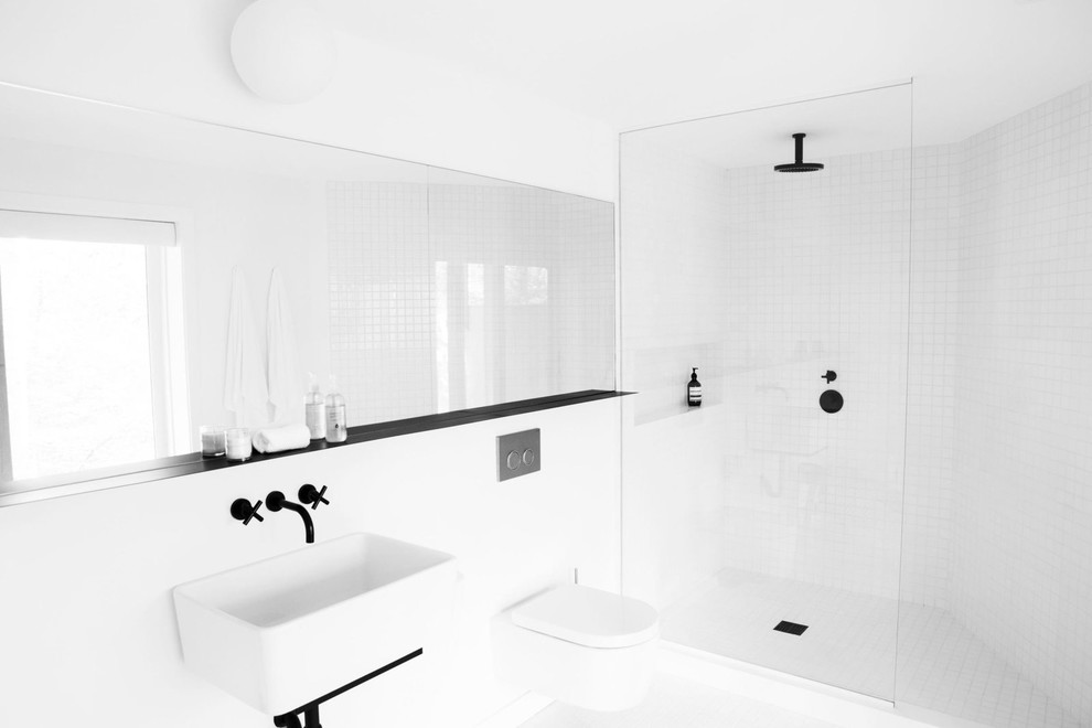 Idéer för mellanstora minimalistiska badrum med dusch, med en vägghängd toalettstol, vit kakel, vita väggar, ett väggmonterat handfat, en hörndusch och med dusch som är öppen