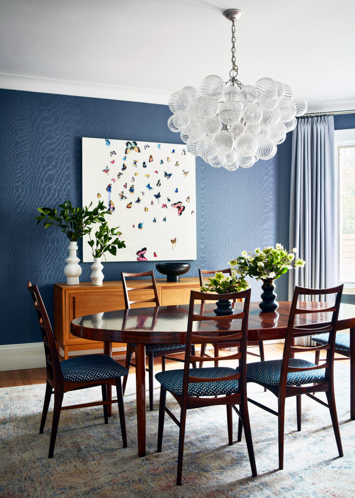 Cette photo montre une salle à manger ouverte sur la cuisine chic avec un mur bleu, un sol en bois brun, un sol marron et du papier peint.