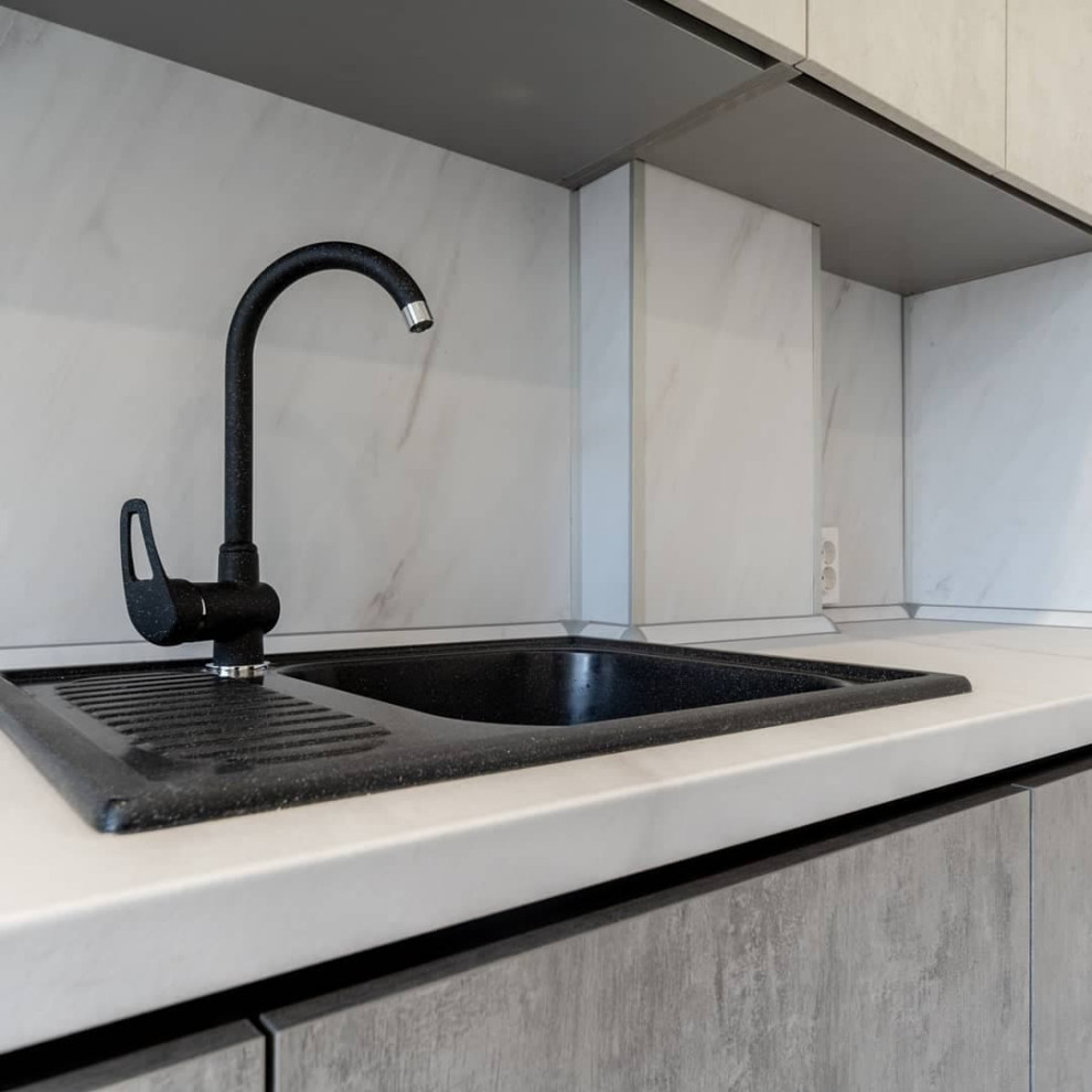 Большая светлая прямая кухня с фасадами под металл и камень