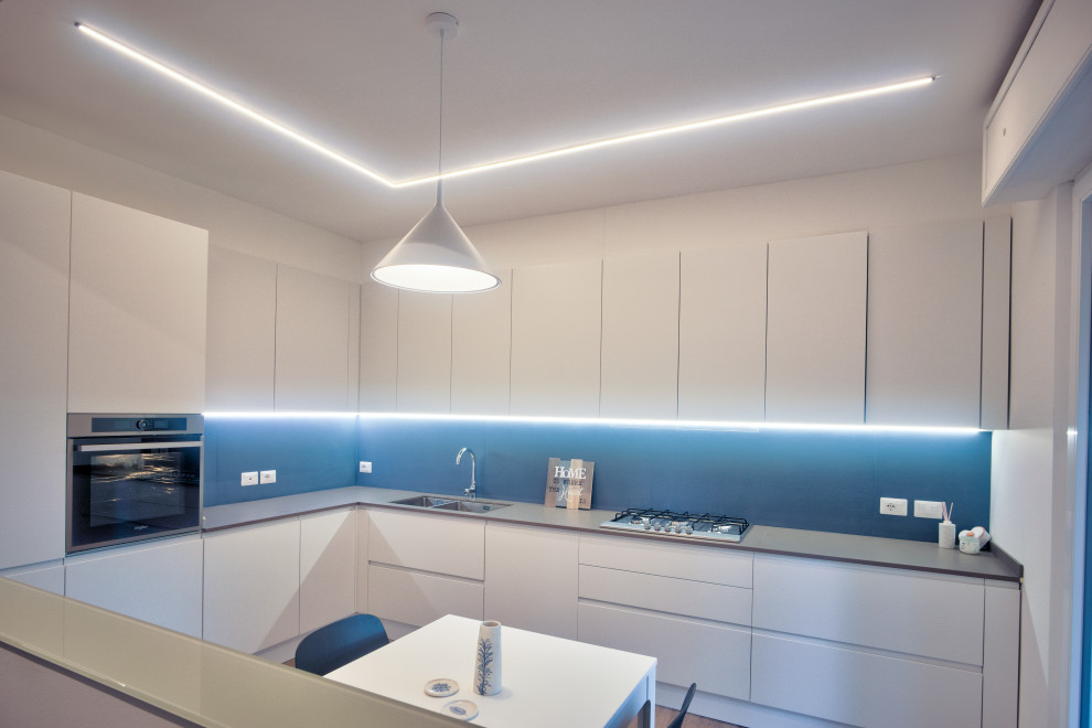 Design ideas for a medium sized contemporary l-shaped kitchen/diner in Other with a submerged sink, flat-panel cabinets, white cabinets, quartz worktops, blue splashback, porcelain splashback, stainless steel appliances, vinyl flooring, no island, beige floors and grey worktops.