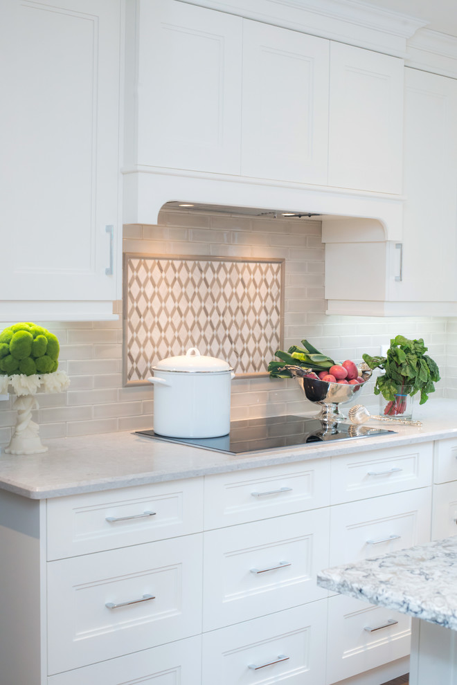 Example of a mid-sized transitional u-shaped eat-in kitchen design in Toronto with shaker cabinets, white cabinets, white backsplash, an island, quartz countertops and stainless steel appliances