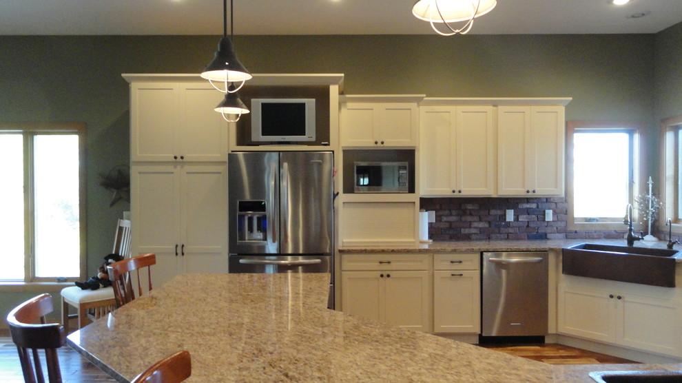Inspiration for a large transitional l-shaped dark wood floor and brown floor open concept kitchen remodel with a farmhouse sink, white cabinets, granite countertops, stainless steel appliances, green walls, an island, shaker cabinets, brown backsplash and stone tile backsplash