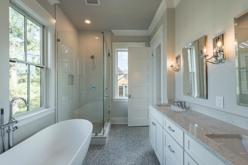 Photo of a transitional master bathroom in Charleston with shaker cabinets, white cabinets, a freestanding tub, a corner shower, subway tile, white walls, an undermount sink and a hinged shower door.