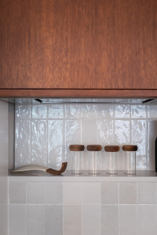 Modern inredning av ett litet linjärt kök med öppen planlösning, med luckor med infälld panel, skåp i mellenmörkt trä och grått stänkskydd