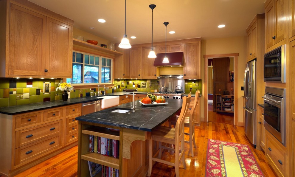 Photo of a large arts and crafts galley separate kitchen in Los Angeles with a farmhouse sink, shaker cabinets, light wood cabinets, soapstone benchtops, green splashback, ceramic splashback, coloured appliances, medium hardwood floors and with island.