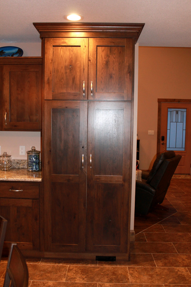 Inspiration for a large rustic l-shaped eat-in kitchen remodel in Chicago with a farmhouse sink, shaker cabinets, dark wood cabinets, granite countertops, stainless steel appliances and an island