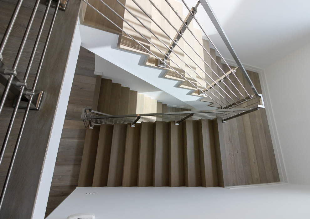 This is an example of a medium sized modern wood floating metal railing staircase in DC Metro with wood risers and tongue and groove walls.
