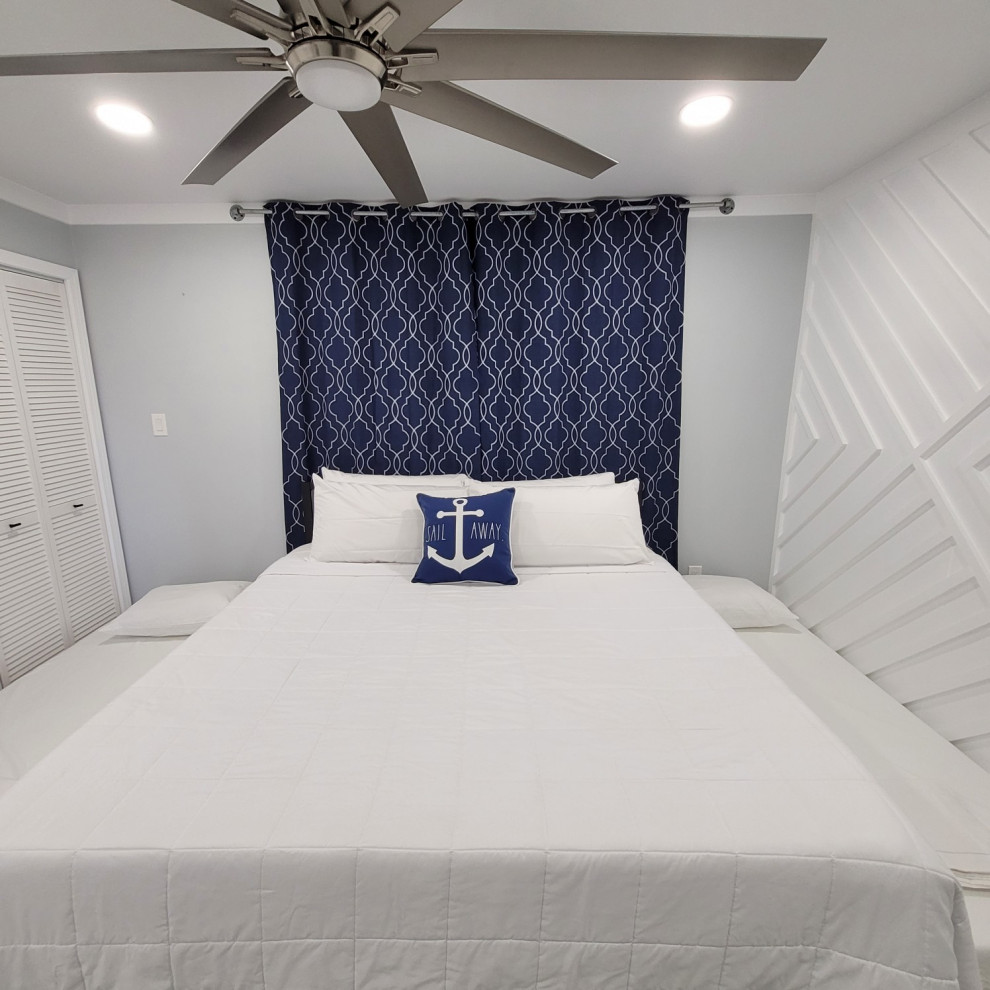 Ejemplo de dormitorio costero con paredes grises, suelo vinílico, suelo gris y madera