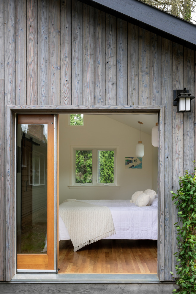 Réalisation d'une petite façade de maison grise minimaliste en bois de plain-pied avec un toit à quatre pans, un toit en shingle et un toit noir.