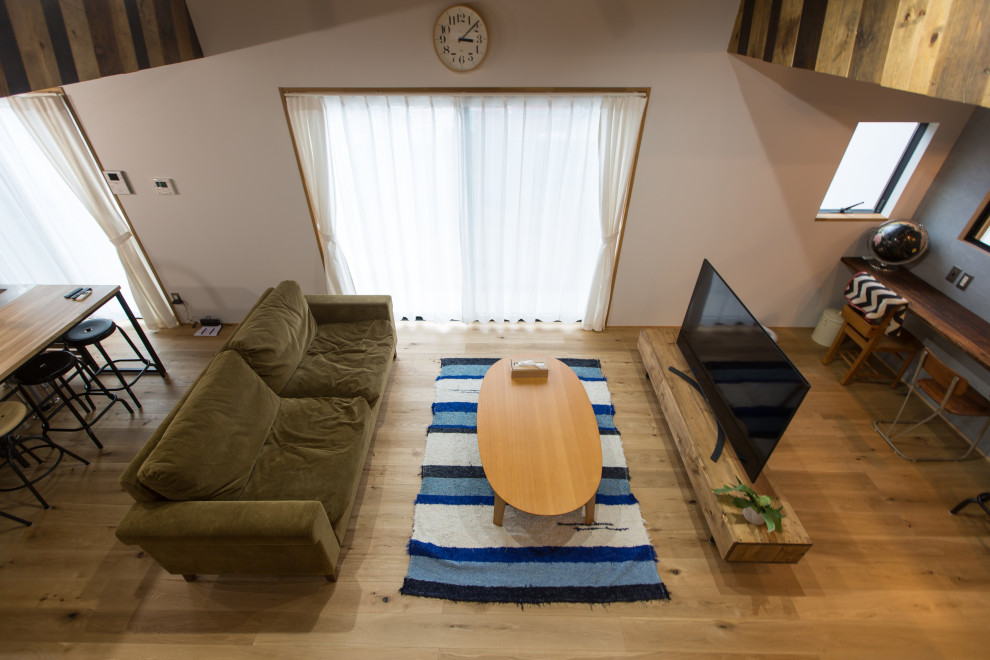 Mid-sized industrial open concept living room in Other with a library, white walls, light hardwood floors, no fireplace, a freestanding tv and beige floor.