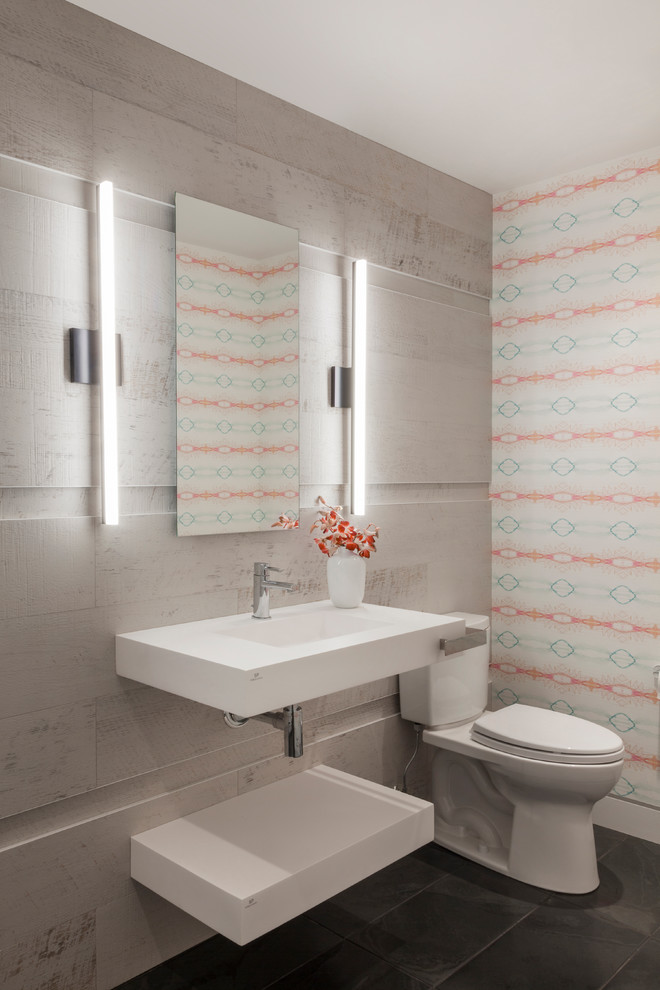 Photo of a mid-sized contemporary powder room in New York with a two-piece toilet, multi-coloured walls, ceramic floors and a wall-mount sink.