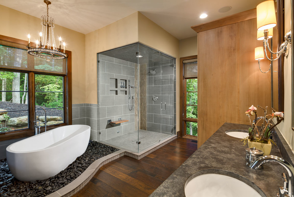 Inspiration for a transitional master gray tile and ceramic tile dark wood floor freestanding bathtub remodel with shaker cabinets, medium tone wood cabinets, a two-piece toilet, yellow walls, an undermount sink, granite countertops and a hinged shower door