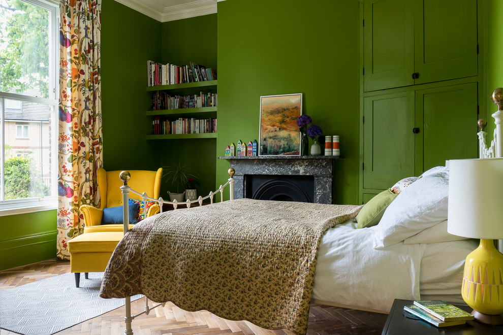 Inspiration for a transitional bedroom in London with green walls, a stone fireplace surround, light hardwood floors, a standard fireplace and beige floor.