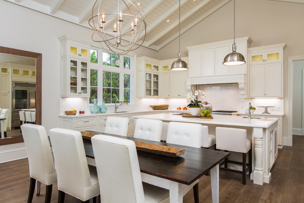Beach style l-shaped eat-in kitchen in Miami with an undermount sink, glass-front cabinets, white cabinets, white splashback, dark hardwood floors and with island.