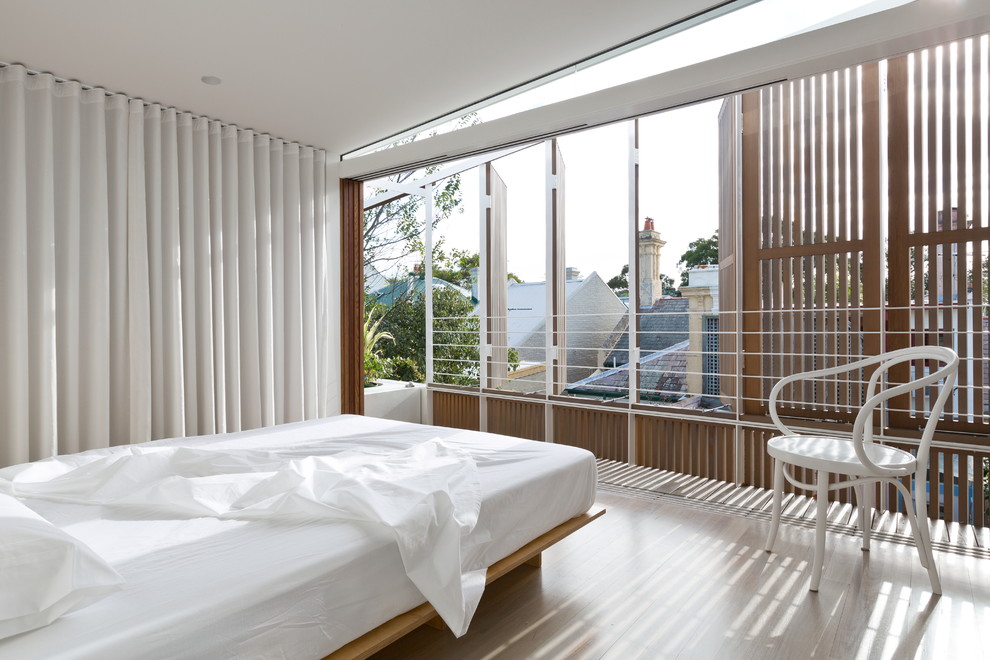 This is an example of a contemporary bedroom in Sydney with white walls and light hardwood floors.
