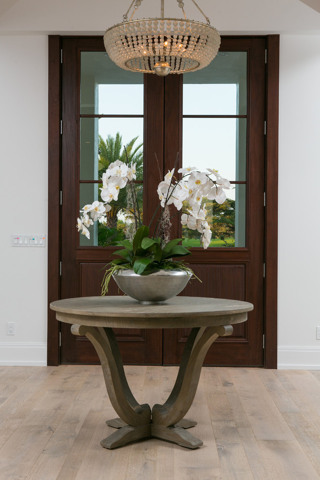 Inspiration for a large tropical foyer in Miami with white walls, light hardwood floors, a double front door and a glass front door.