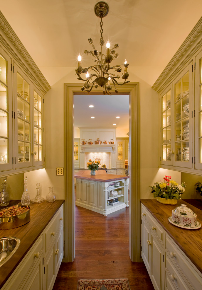 Traditional kitchen pantry in Philadelphia with glass-front cabinets and wood benchtops.