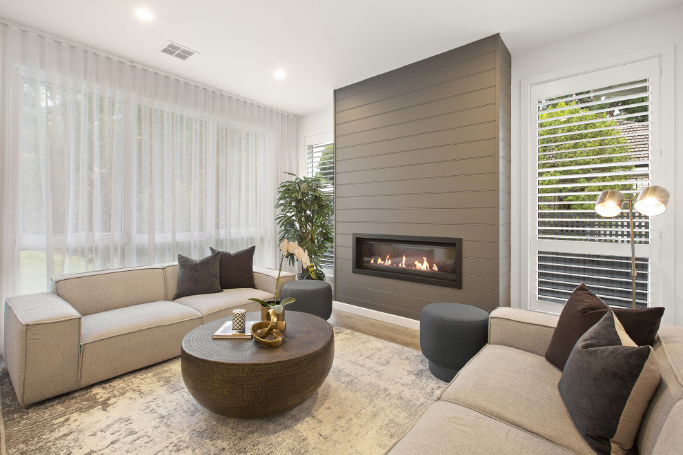 Photo of a mid-sized transitional formal enclosed living room in Melbourne with white walls, medium hardwood floors, a ribbon fireplace, a wood fireplace surround, no tv and beige floor.