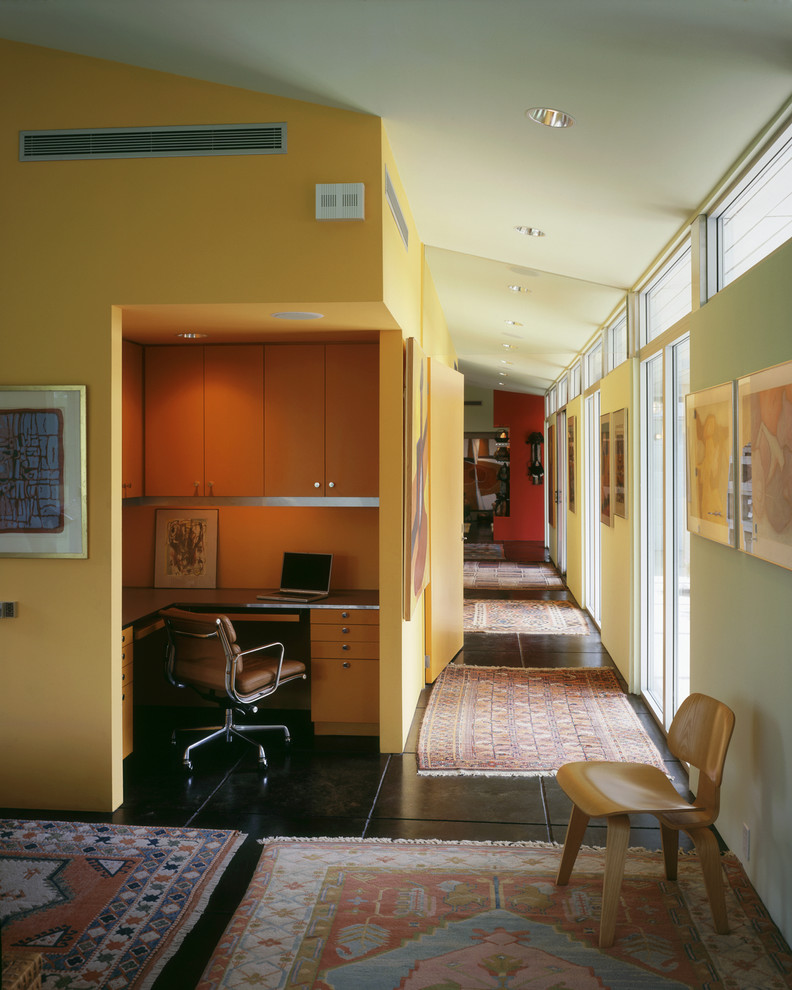 Inspiration for a midcentury home office in Austin with yellow walls and black floor.