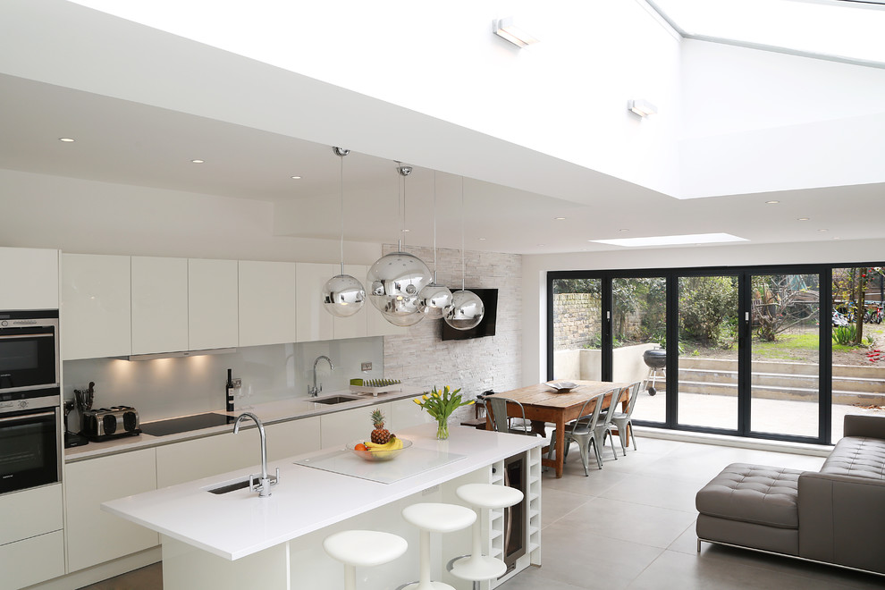 Design ideas for a modern kitchen in London with a single-bowl sink, glass-front cabinets, white cabinets, grey splashback, glass sheet splashback, stainless steel appliances and with island.