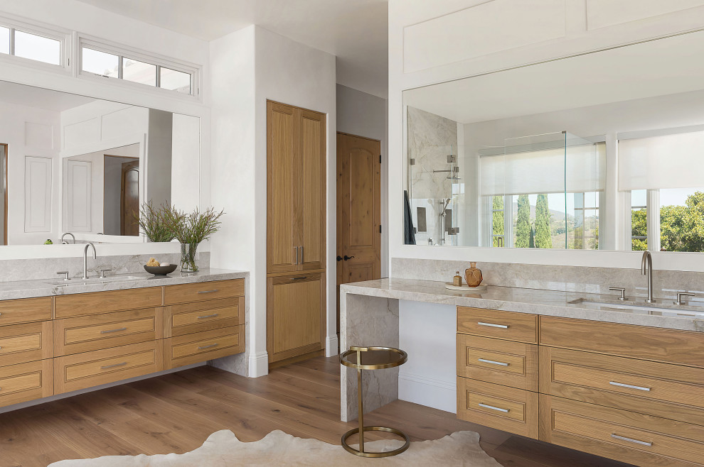 Design ideas for a large modern master bathroom in San Diego with louvered cabinets, beige cabinets, a freestanding tub, a one-piece toilet, beige tile, stone slab, light hardwood floors, an undermount sink, quartzite benchtops and beige benchtops.