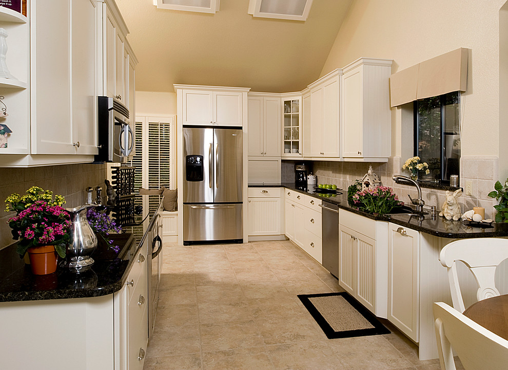 Example of a mid-sized transitional galley porcelain tile eat-in kitchen design with shaker cabinets, white cabinets, granite countertops, beige backsplash, porcelain backsplash and stainless steel appliances